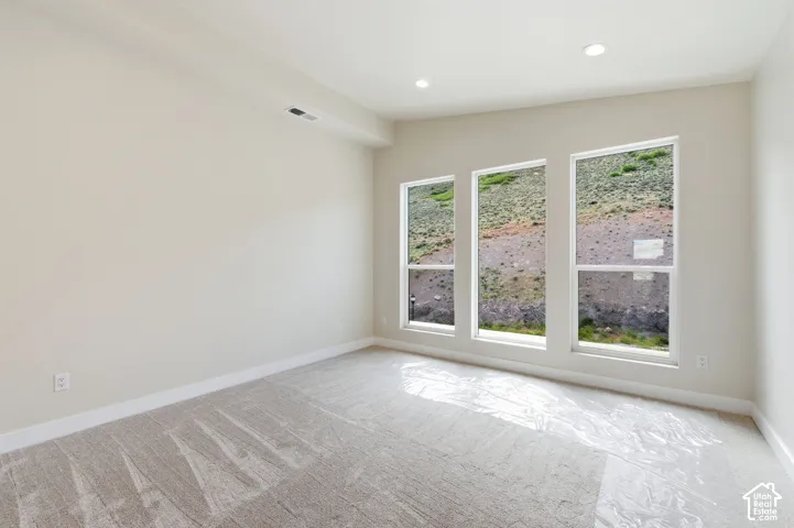 Spacious room featuring three large windows, recessed lighting, neutral wall paint, white baseboards, and light-toned carpet