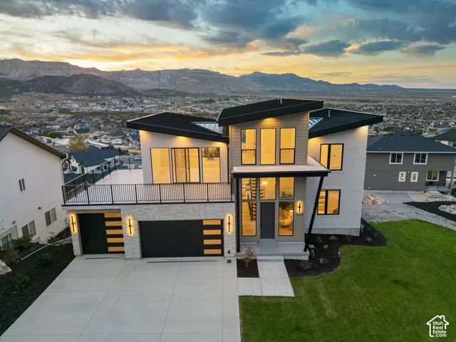 Modern architectural design featuring expansive window panels, a multi-level deck, and integrated garage doors