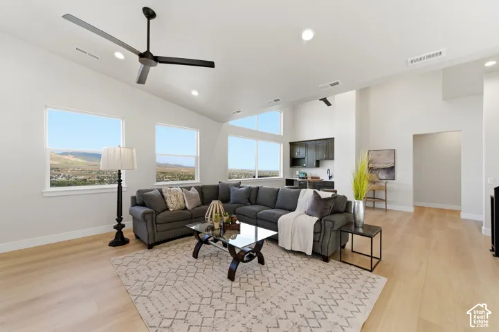 Spacious living area featuring a vaulted ceiling with a modern ceiling fan, recessed lighting, and numerous windows