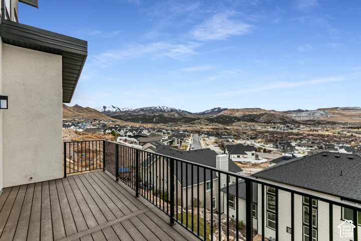 Spacious outdoor balcony with composite decking and black metal railings, offering expansive mountain and neighborhood scenery