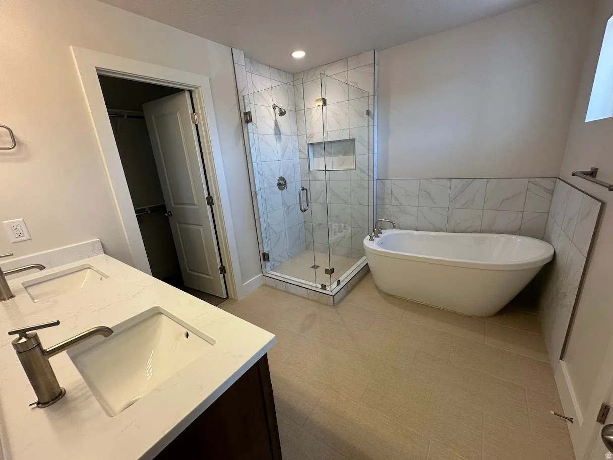 Contemporary bathroom featuring a freestanding soaking tub, a frameless glass shower enclosure with tile surround and built-in niche, and a double vanity with undermount sinks and quartz countertops