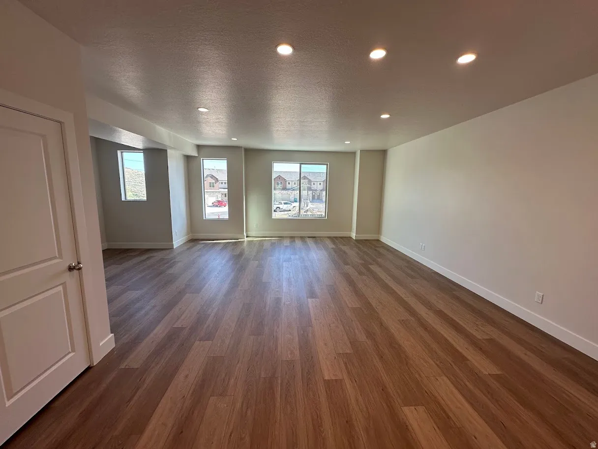 Spacious room featuring wood-finish flooring, recessed lighting, and multiple windows