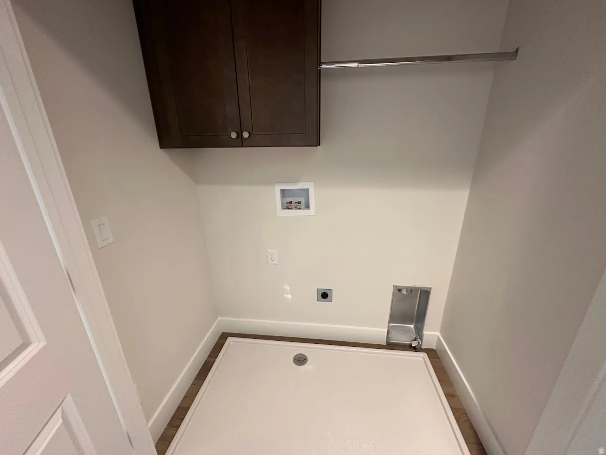 Dedicated laundry space with wood-finish flooring, white baseboards, and neutral wall paint