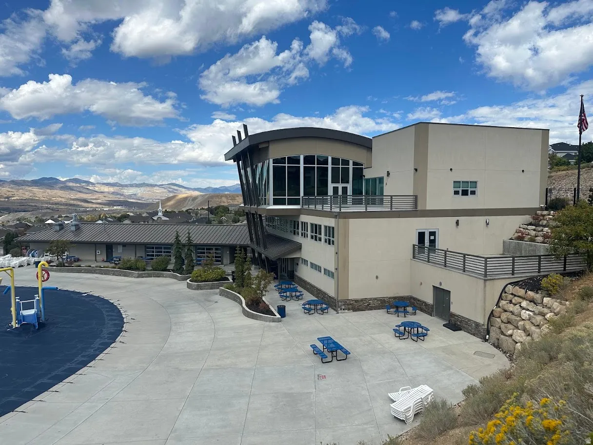 Multi-level commercial structure featuring expansive windows, multiple outdoor patio areas with metal railings, and a large paved courtyard