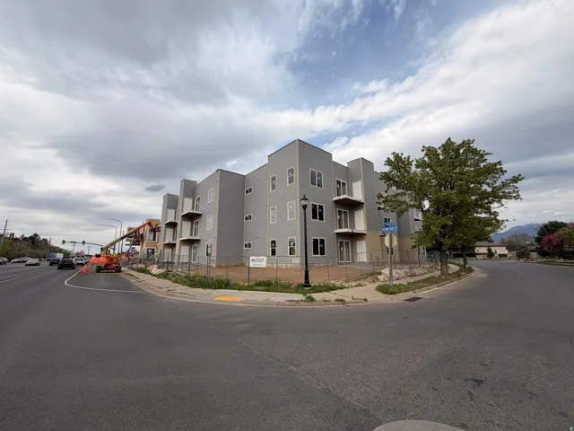 New construction multi-story building featuring light gray siding and multiple balconies with white railings