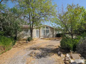 Single-story residence featuring a gravel driveway and surrounding mature trees