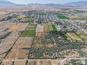 Expansive aerial perspective showcasing a rural landscape with agricultural fields, scattered residential development, and distant mountain ranges under a clear sky