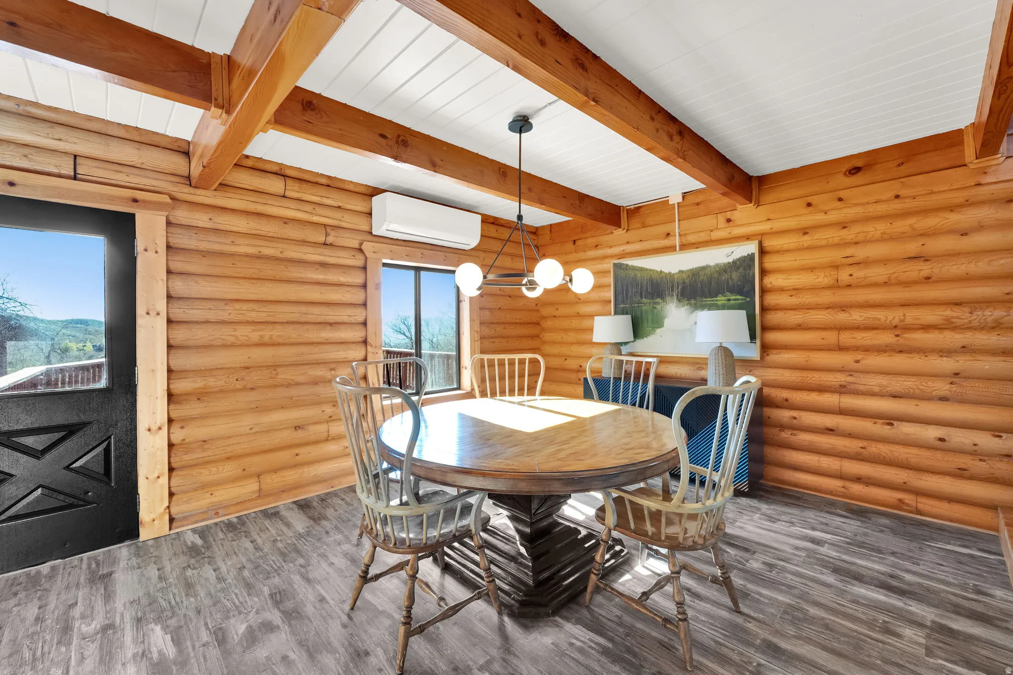 Interior space featuring wood-finish flooring, log walls, and exposed wood beams with a white plank ceiling