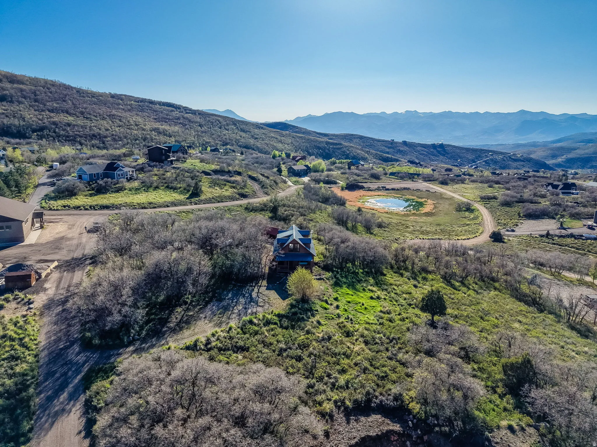 Expansive elevated property featuring a prominent residence, surrounded by abundant natural vegetation and a distant mountain range