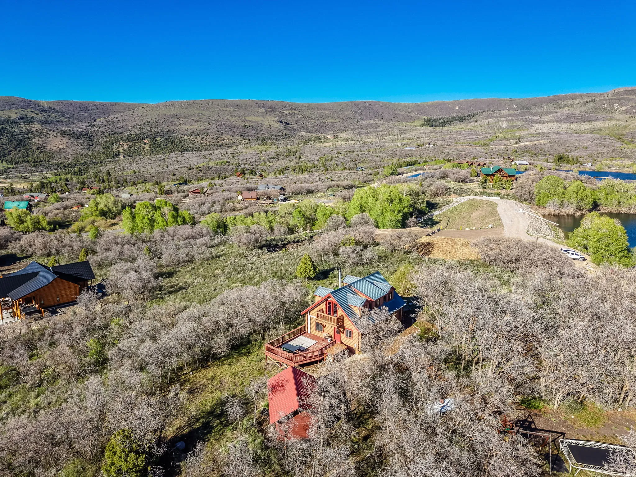 Expansive hillside property featuring a rustic-style residence with a large outdoor deck and vibrant blue roofing