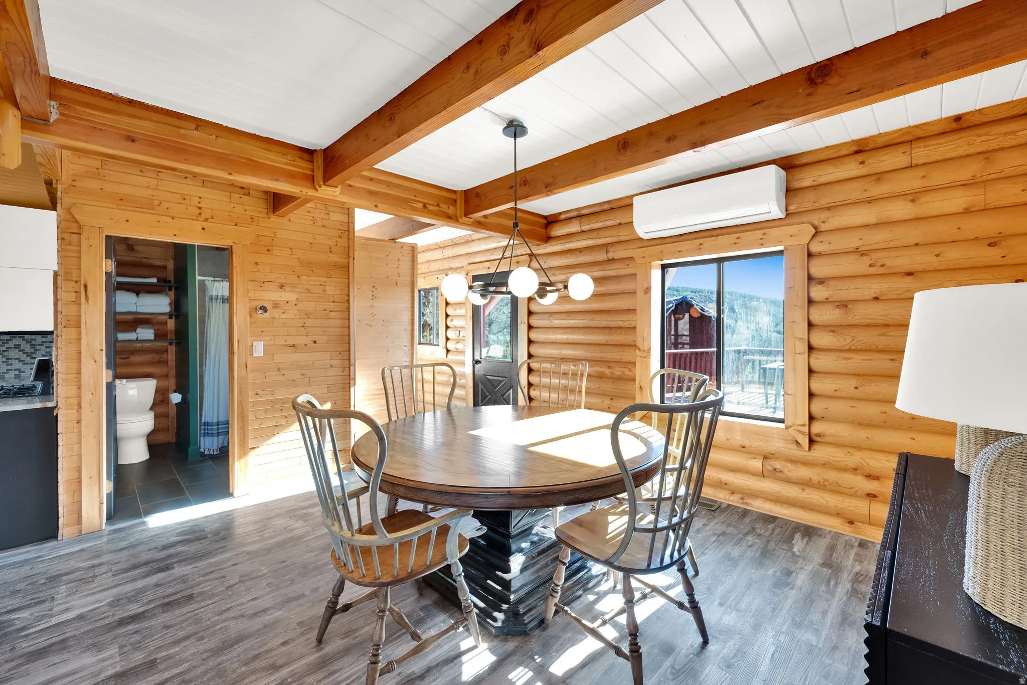 Dining area featuring log walls, exposed wood beams, and wood-finish flooring