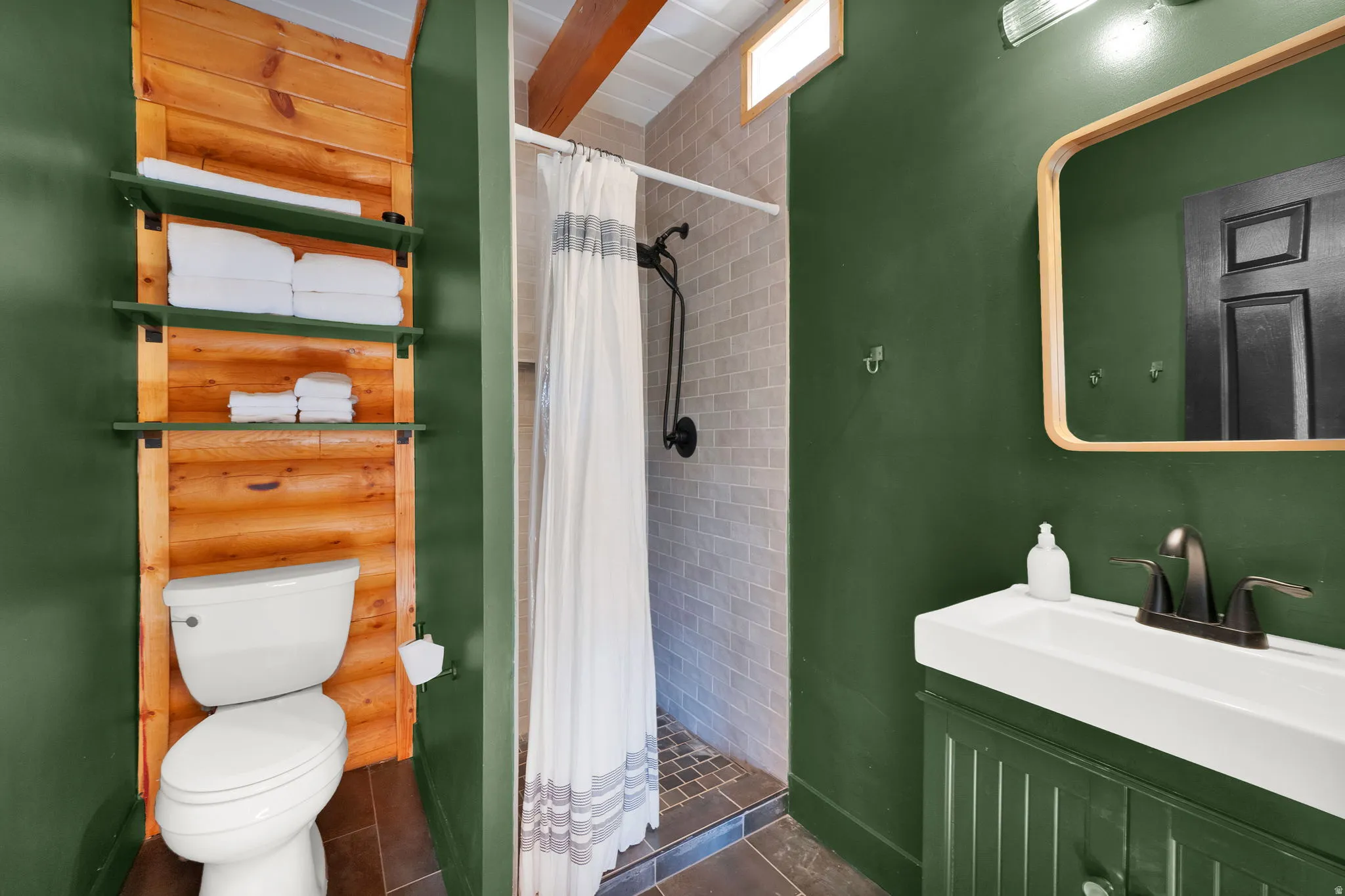 Bathroom featuring a walk-in shower with subway tile, wood-finish flooring, a vanity with fluted paneling, and an overhead transom window
