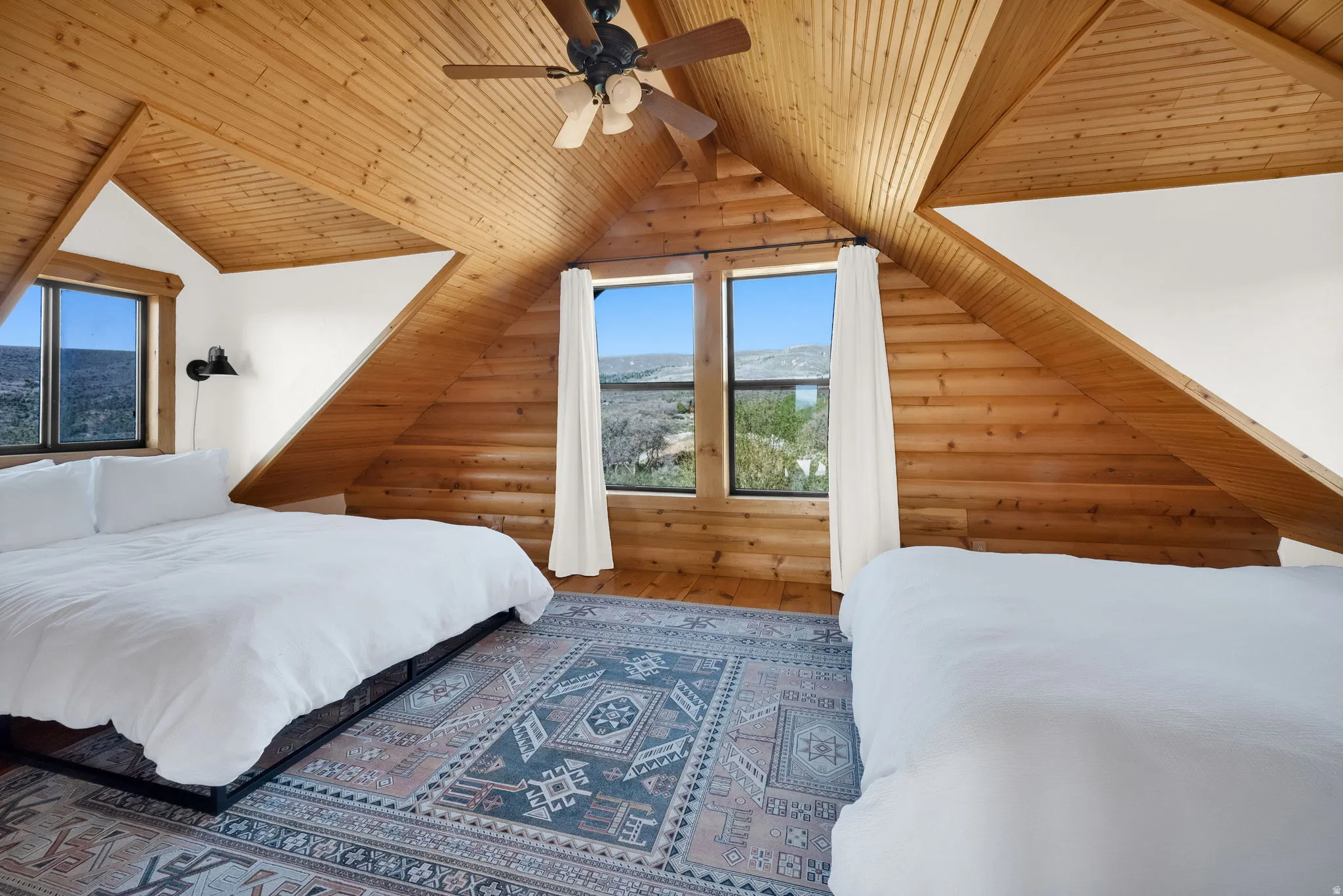 Vaulted wood-paneled ceilings with exposed beams, wood-finish flooring, and multiple windows providing natural light
