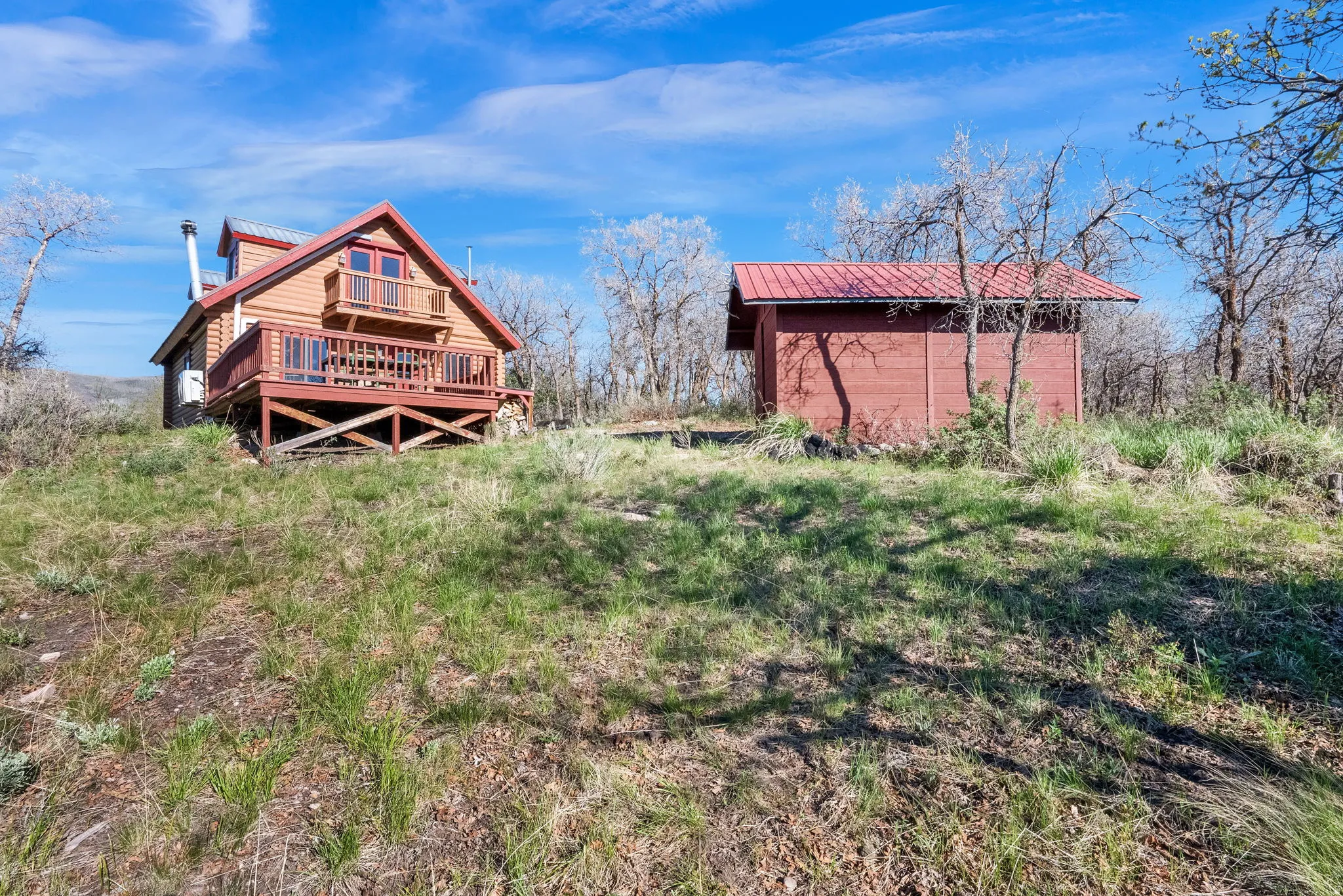 Wood-sided cabin featuring an elevated deck and an upper-level balcony