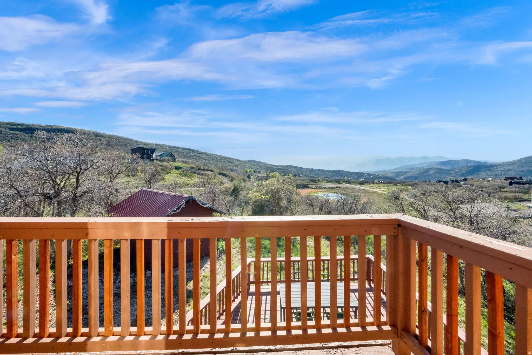 Expansive outdoor deck with natural wood railing overlooking a distant pond and rolling hills