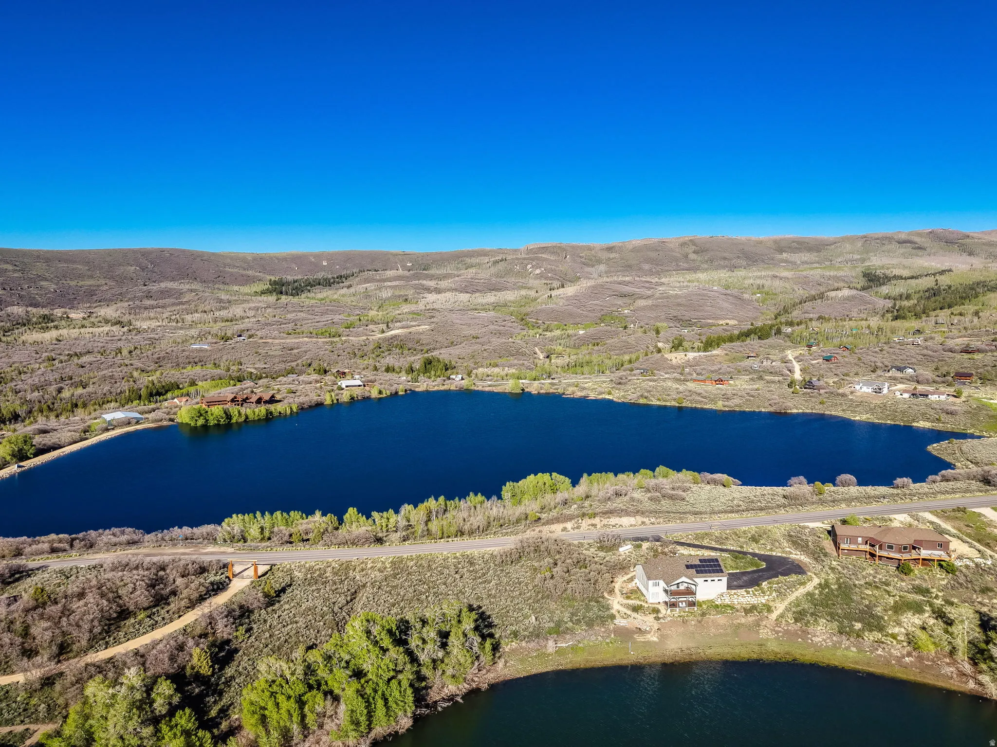 Expansive aerial capturing a large lake surrounded by rolling hills