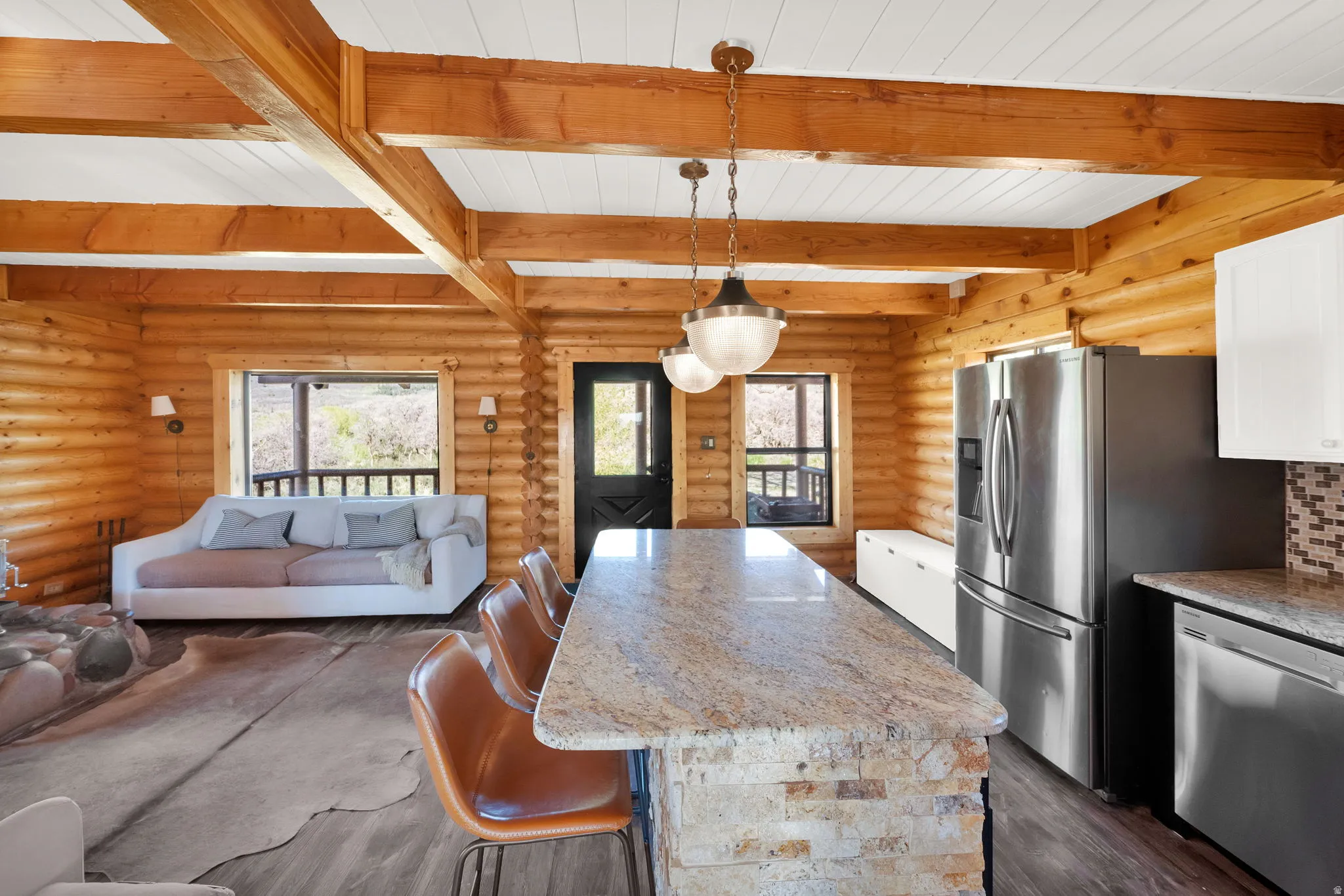 Open-concept living space featuring wood-finish flooring and exposed wood beams