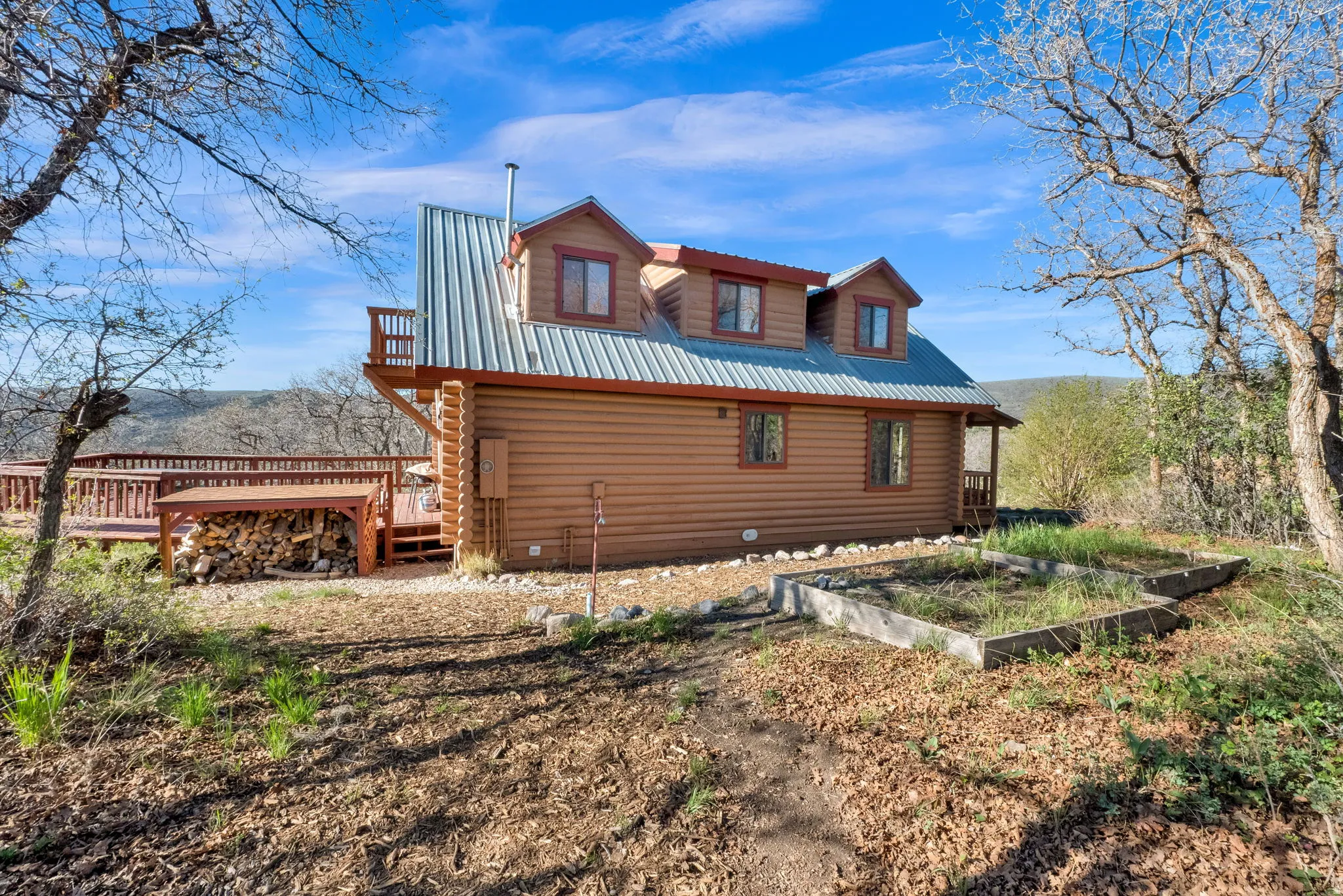 Log-sided residence featuring a metal roof, multiple dormer windows, and a chimney