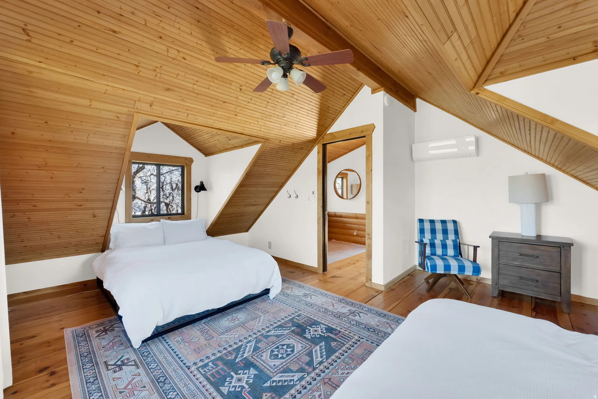 Attic bedroom featuring pitched wood-finish ceilings and exposed wood-finish flooring