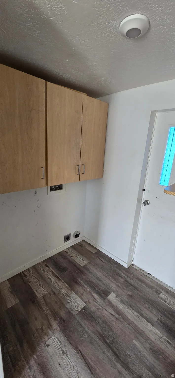 Utility area featuring wood-finish flooring, overhead cabinetry, and laundry hookups