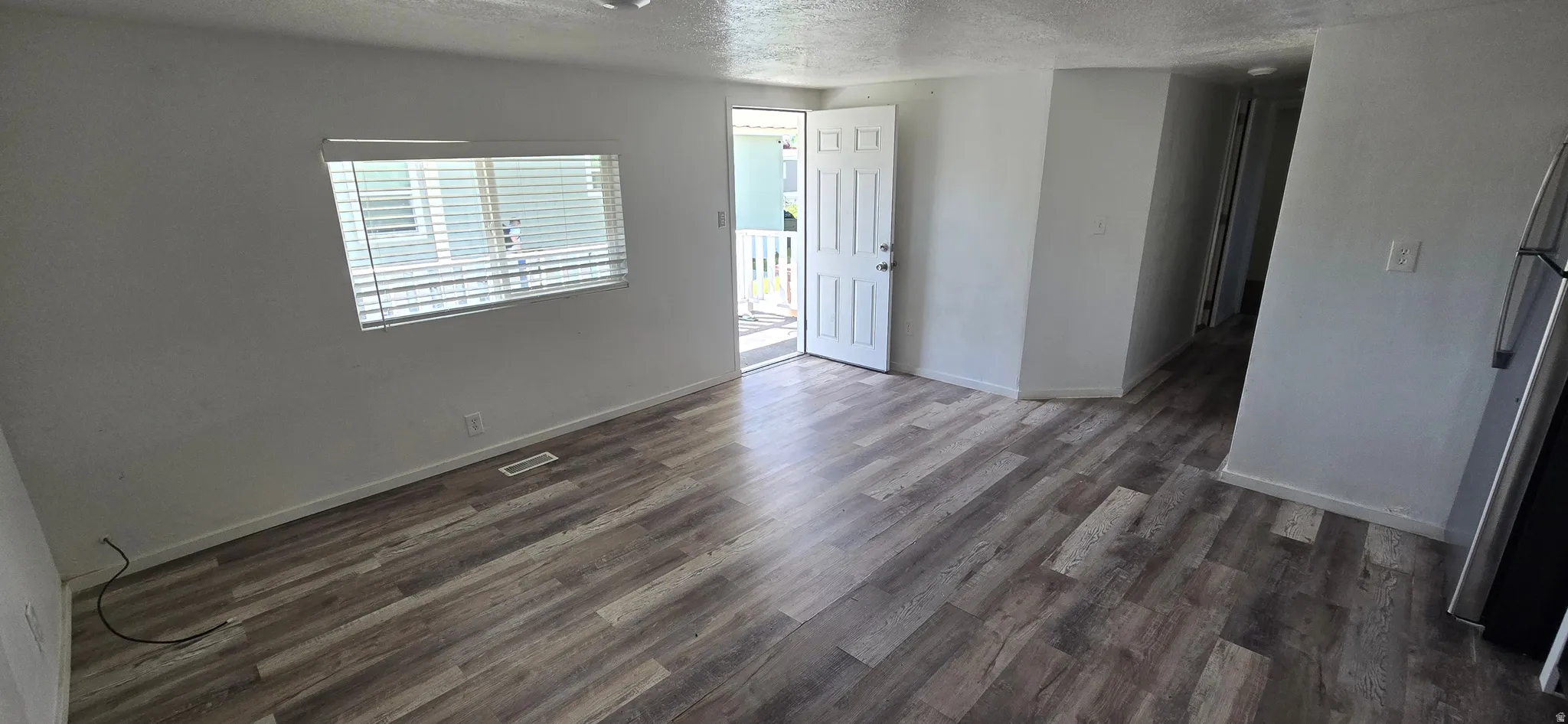 Open concept living area featuring wood-finish flooring, white wall finishes, and a white paneled entry door