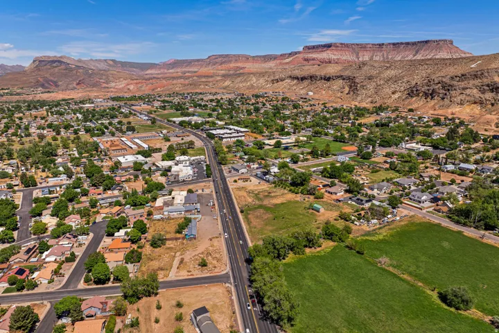 Expansive aerial view of a community featuring residential properties, verdant green spaces, and a prominent roadway