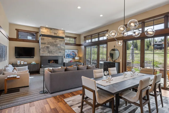 Open-concept living space featuring a stone fireplace with a contemporary linear hearth, rich wood-finish flooring, and expansive glass sliding doors