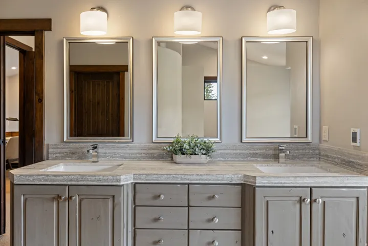 Double vanity featuring a light gray countertop with integrated sinks, brushed nickel faucets, and framed mirrors