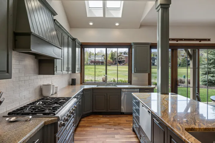 Kitchen featuring a gas range, dark wood-finish cabinetry, light subway tile backsplash, and light-colored countertops with natural variations