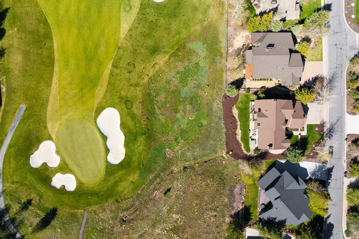 Aerial perspective showcasing a residential property with direct proximity to a golf course