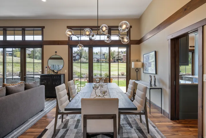 Open-concept living and dining area featuring wood-finish flooring, a modern linear chandelier, and expansive sliding glass doors