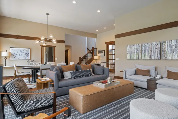 Spacious living area featuring high ceilings, exposed wood beams, recessed lighting, and wood-trim doorways