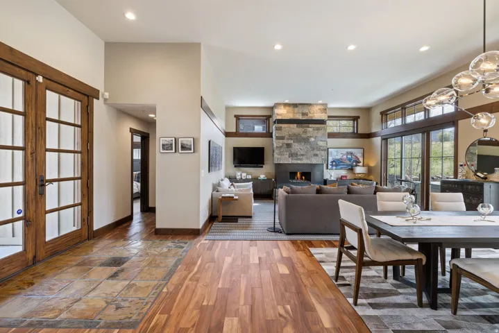 Open-concept living space featuring wood-finish flooring, a stone-clad fireplace, and expansive glass sliding doors