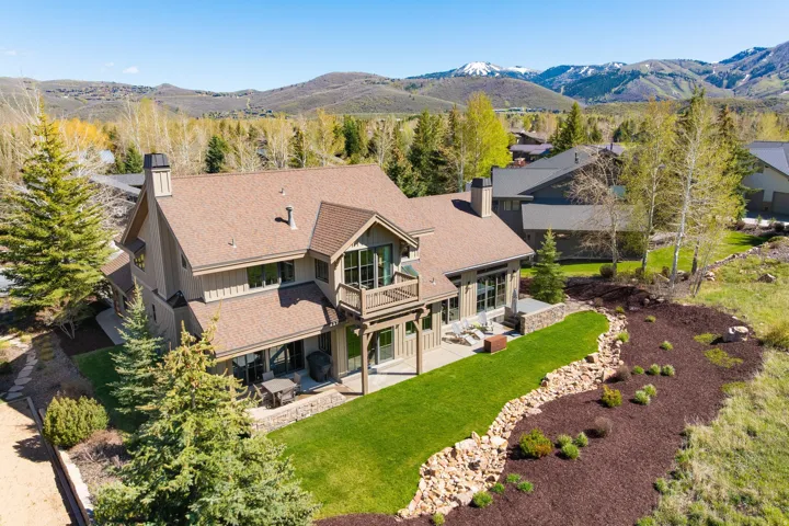 Contemporary multi-story residence featuring a prominent balcony, a lower-level patio, and extensive landscaping