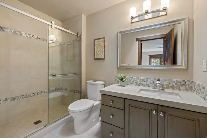 Bathroom featuring a glass-enclosed shower with tile surround and decorative mosaic accents