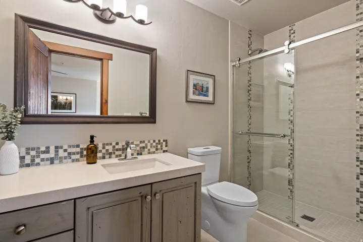 Bathroom featuring a single vanity with a solid surface countertop, an undermount sink, and a rustic wood-finish cabinet