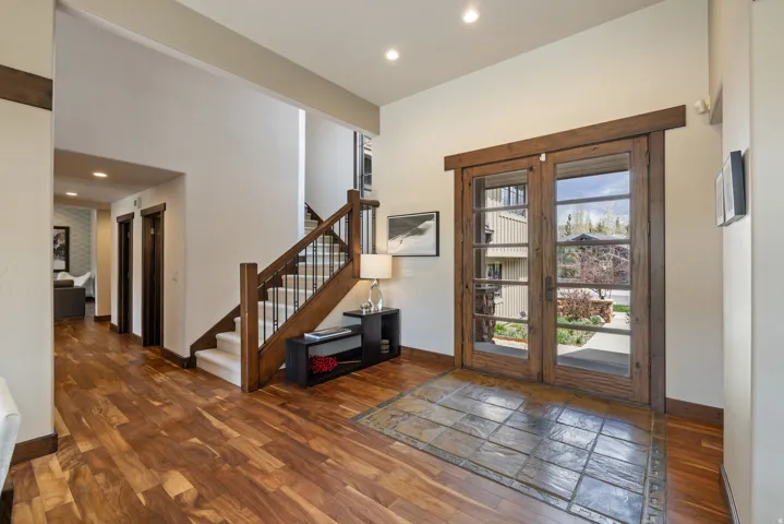 Entryway featuring wood-finish flooring, a grand staircase with wrought iron balusters, a tiled entry area, and double glass-paned doors