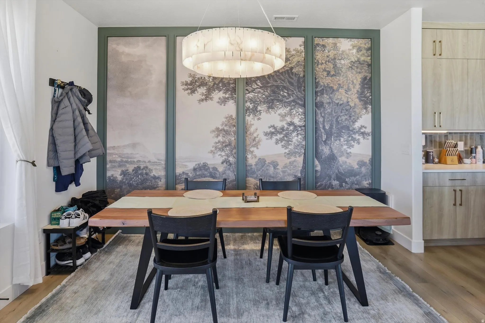Dining area featuring a contemporary chandelier, a built-in wall mural, and wood-finish flooring