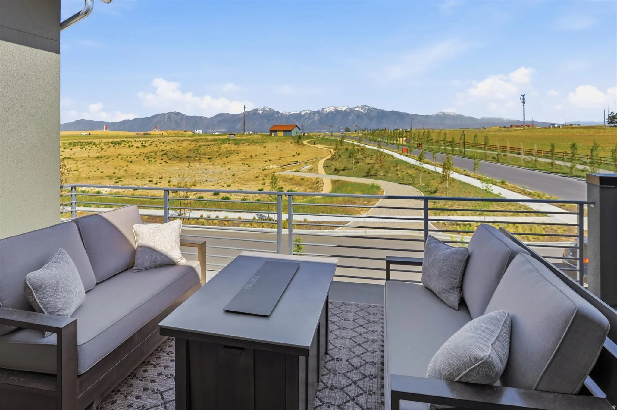 Outdoor balcony featuring a horizontal metal railing and a partial stucco wall
