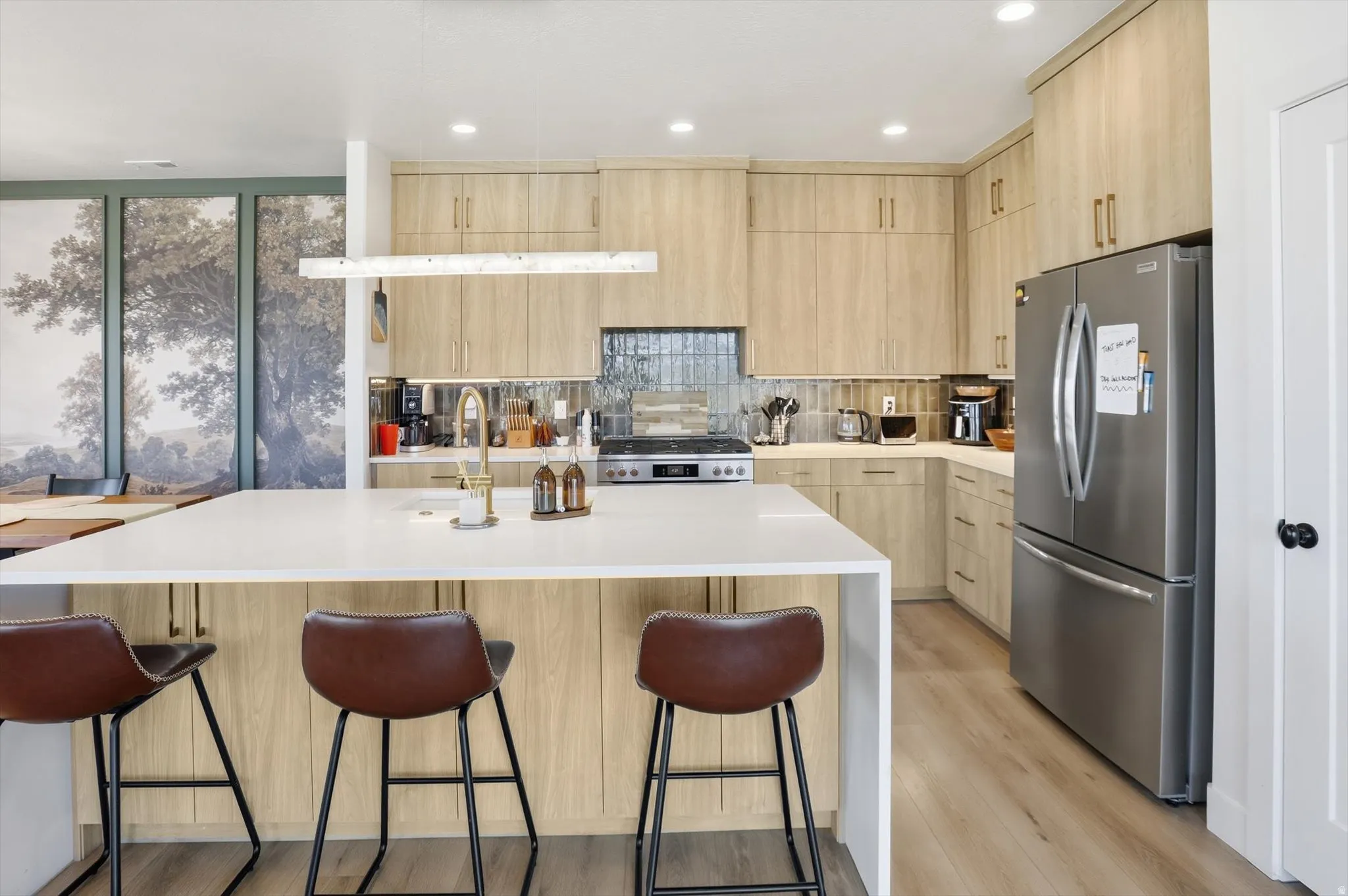 Spacious kitchen featuring a large island with seating, wood-finish cabinetry, stainless steel appliances, a tile backsplash, and recessed lighting