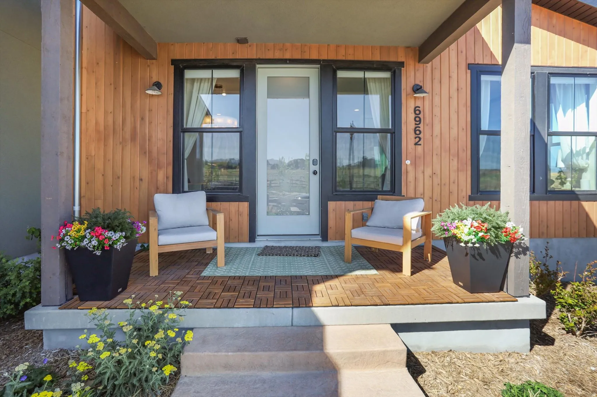 Covered front porch featuring wood-finish siding and dark-trimmed windows