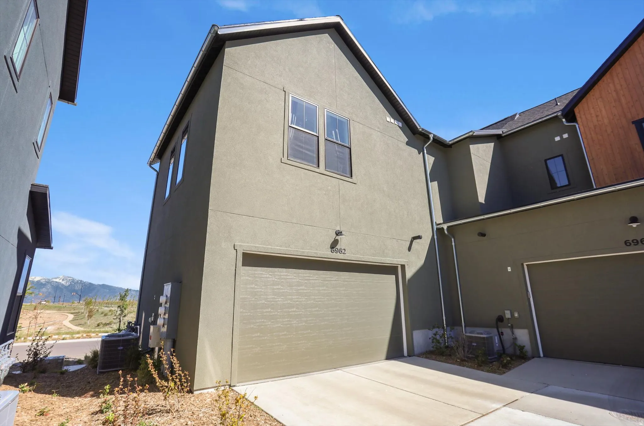 Contemporary stucco exterior featuring a two-car garage with a textured door