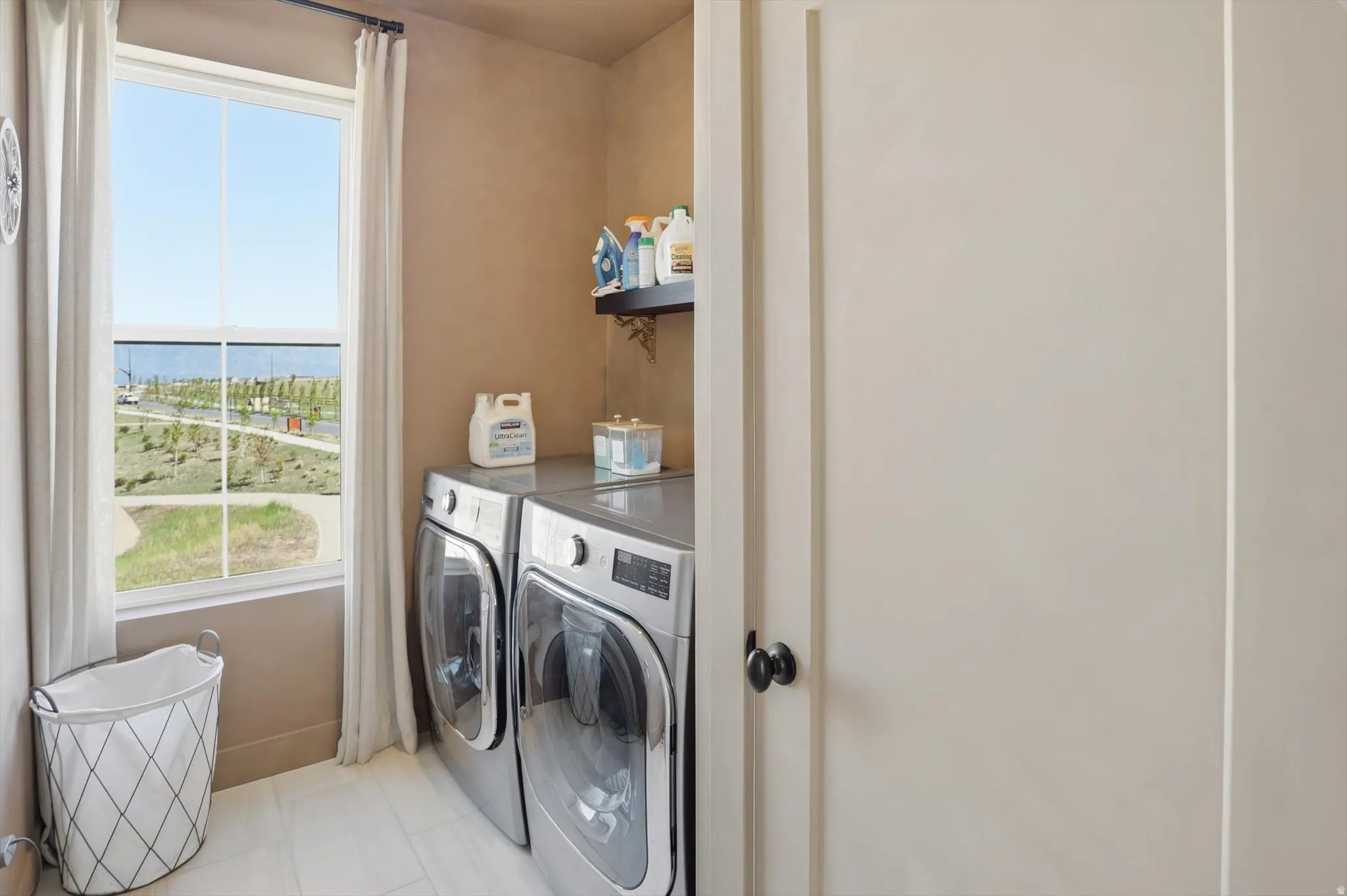Dedicated laundry area featuring a large window, tiled flooring, built-in shelving, and neutral wall tones