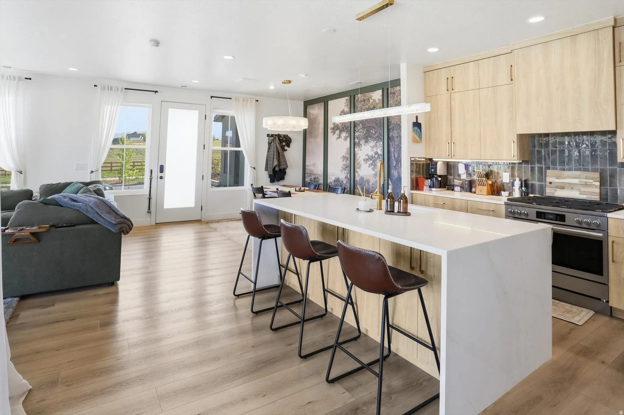 Open-concept living area featuring wood-finish flooring and a white kitchen island with seating