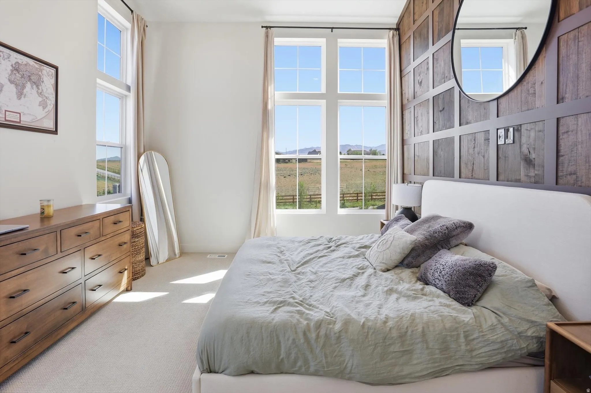 Bedroom featuring large windows, wood plank accent wall, neutral-toned carpeting, and a built-in recessed light fixture