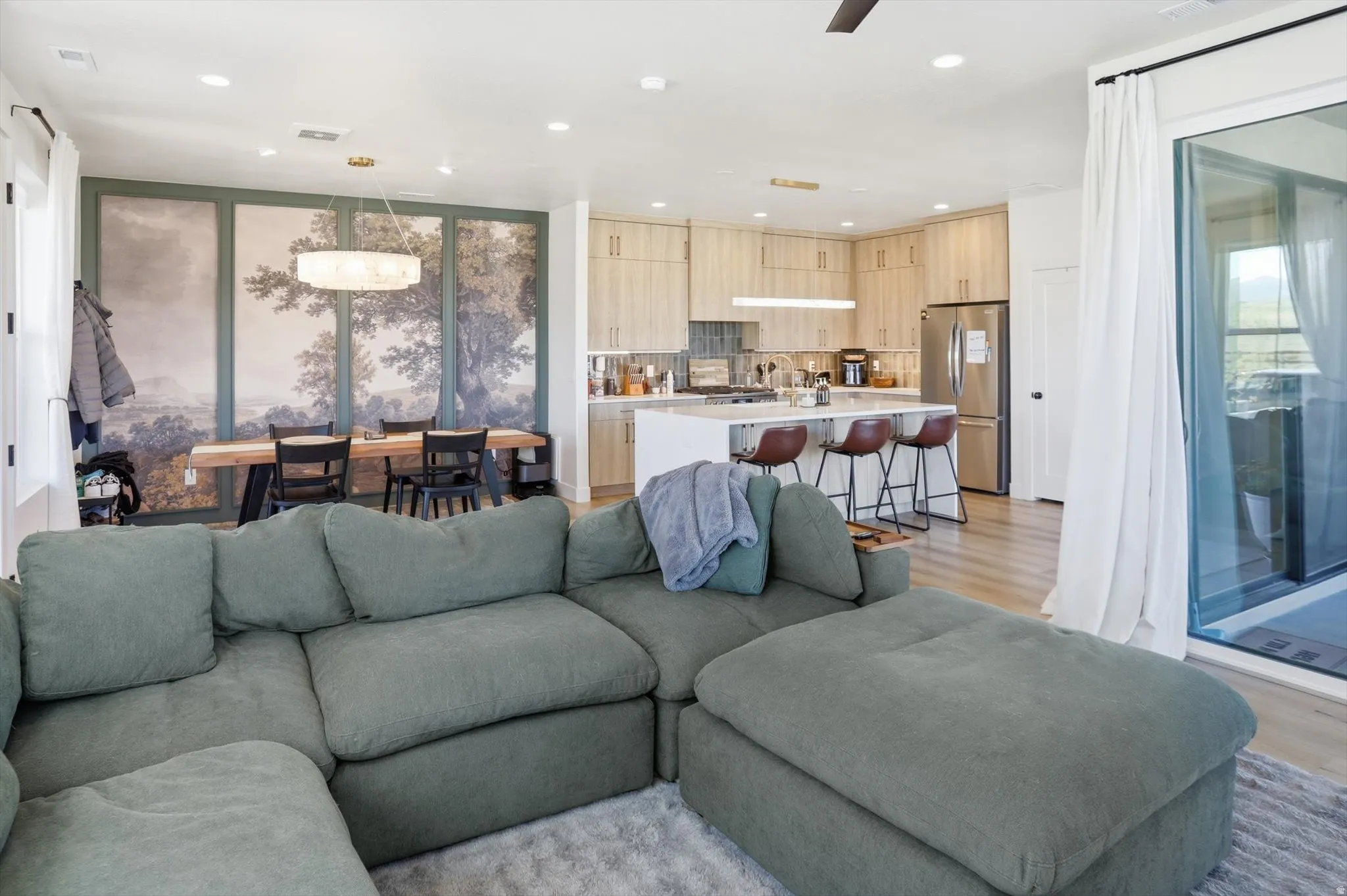 Open-concept living space featuring wood-finish flooring, recessed lighting, and a sliding glass door
