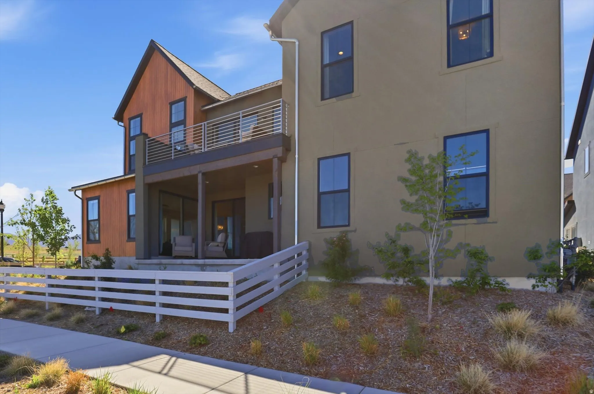 Modern multi-level exterior featuring wood-paneled siding, stucco, and dark-framed windows