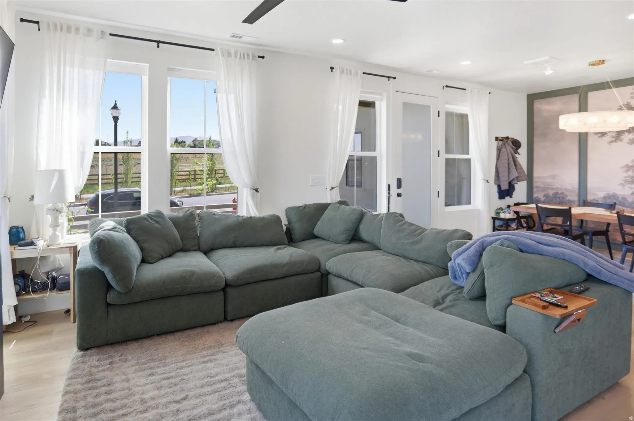 Open-concept living space featuring light wood-finish flooring, recessed lighting, and a contemporary ceiling fan
