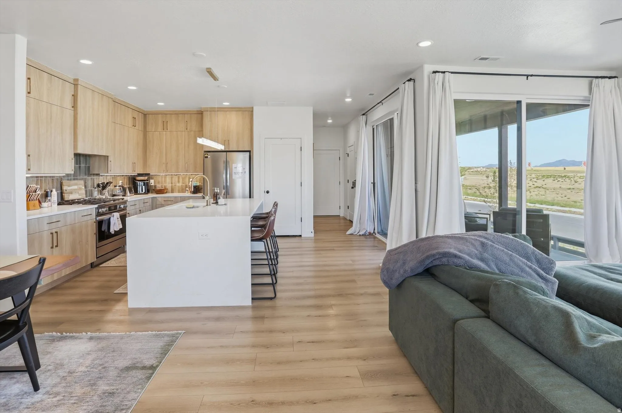 Modern kitchen featuring wood-finish cabinetry, stainless steel appliances, and a central island with countertop seating