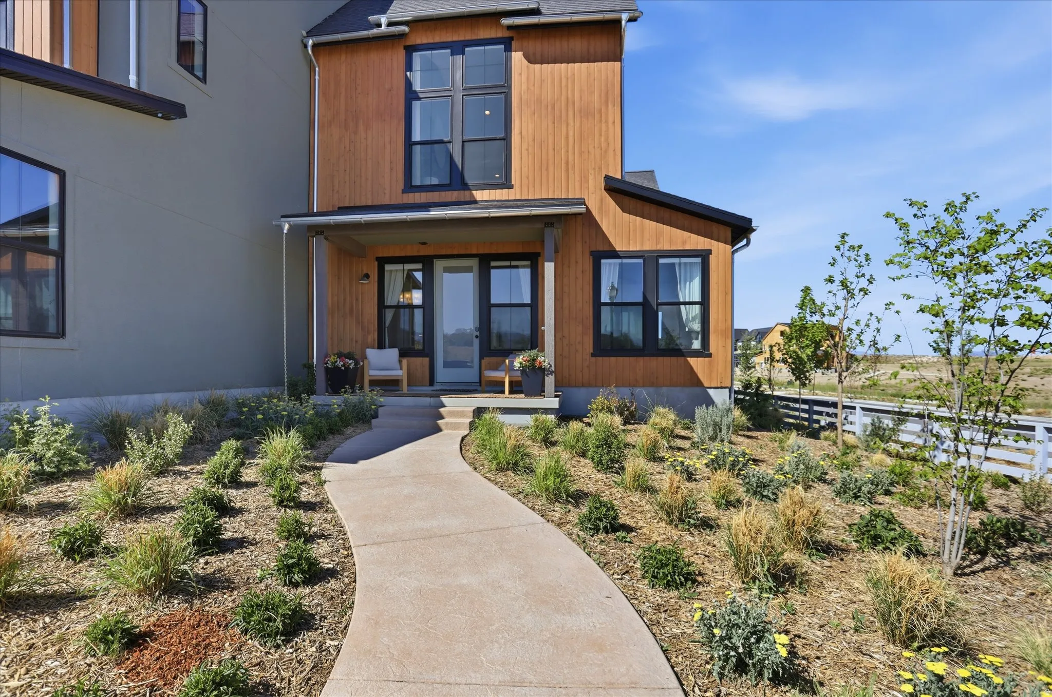 Modern facade featuring a covered entry, vertical wood-finish siding, and dark-framed windows